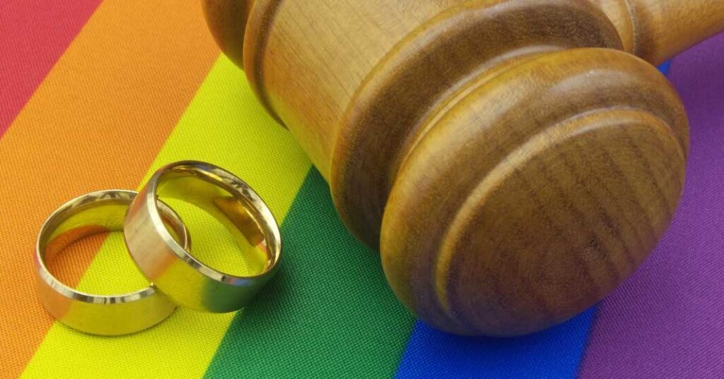 Image of a gavel and rings on top of a LGBTQ+ flag